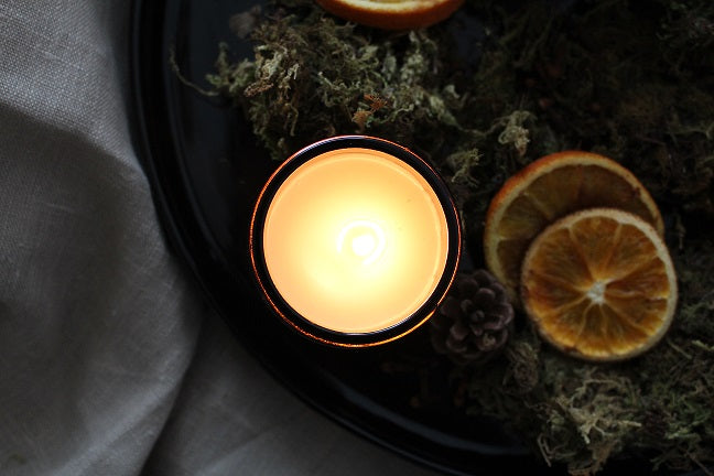 Festive Table Orange + Clove  Amber Candle alight.