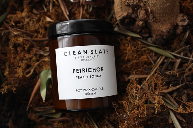 Petrichor teak and tonka scented candle in an amber glass jar.