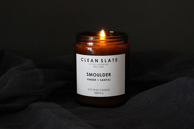 Smoulder Amber + Santal candle in an abmber jar alight.