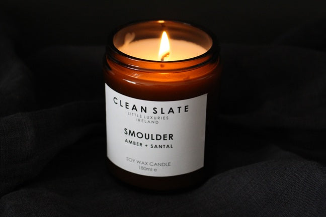 Smoulder Amber + Santal candle in an abmber jar alight.