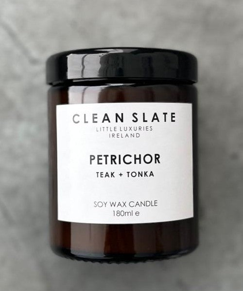 Petrichor teak and tonka scented candle in an amber glass jar.