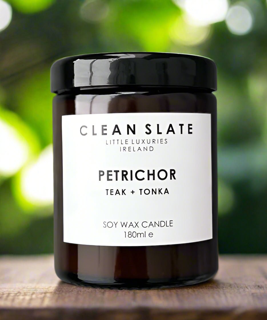 Petrichor teak and tonka scented candle in an amber glass jar.