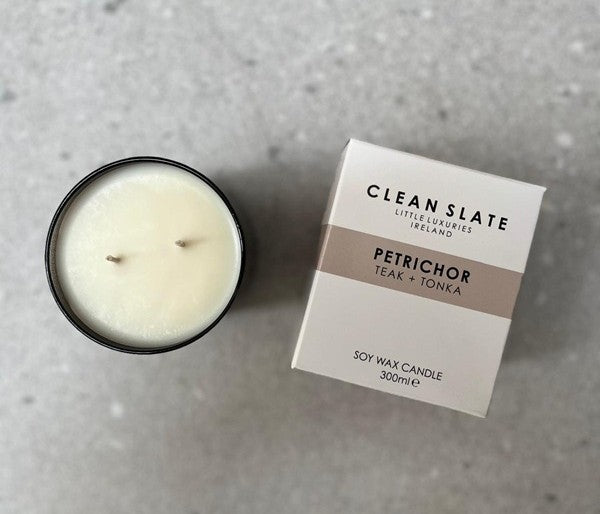 Petrichor teak and tonka scented candle in a dark glass jar with box.