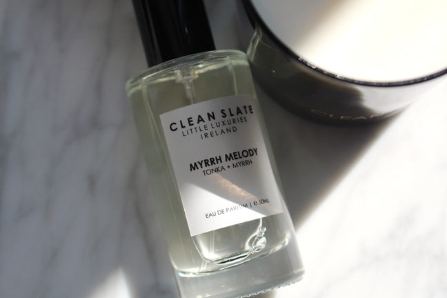 Close-up of the Myrrh Melody Eau De Parfum 50ML bottle next to a candle.